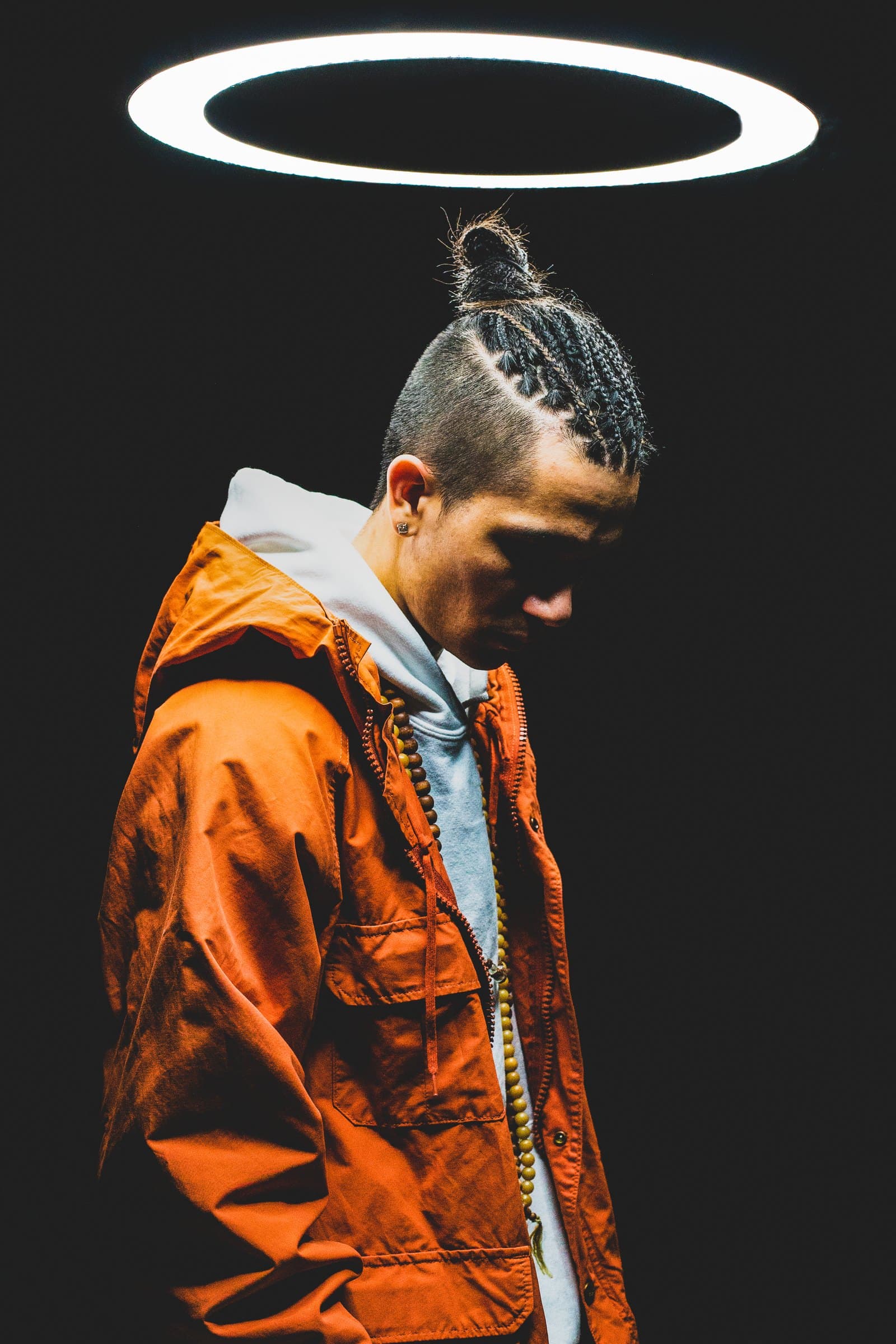 Bdice in an orange jacket under a ring light