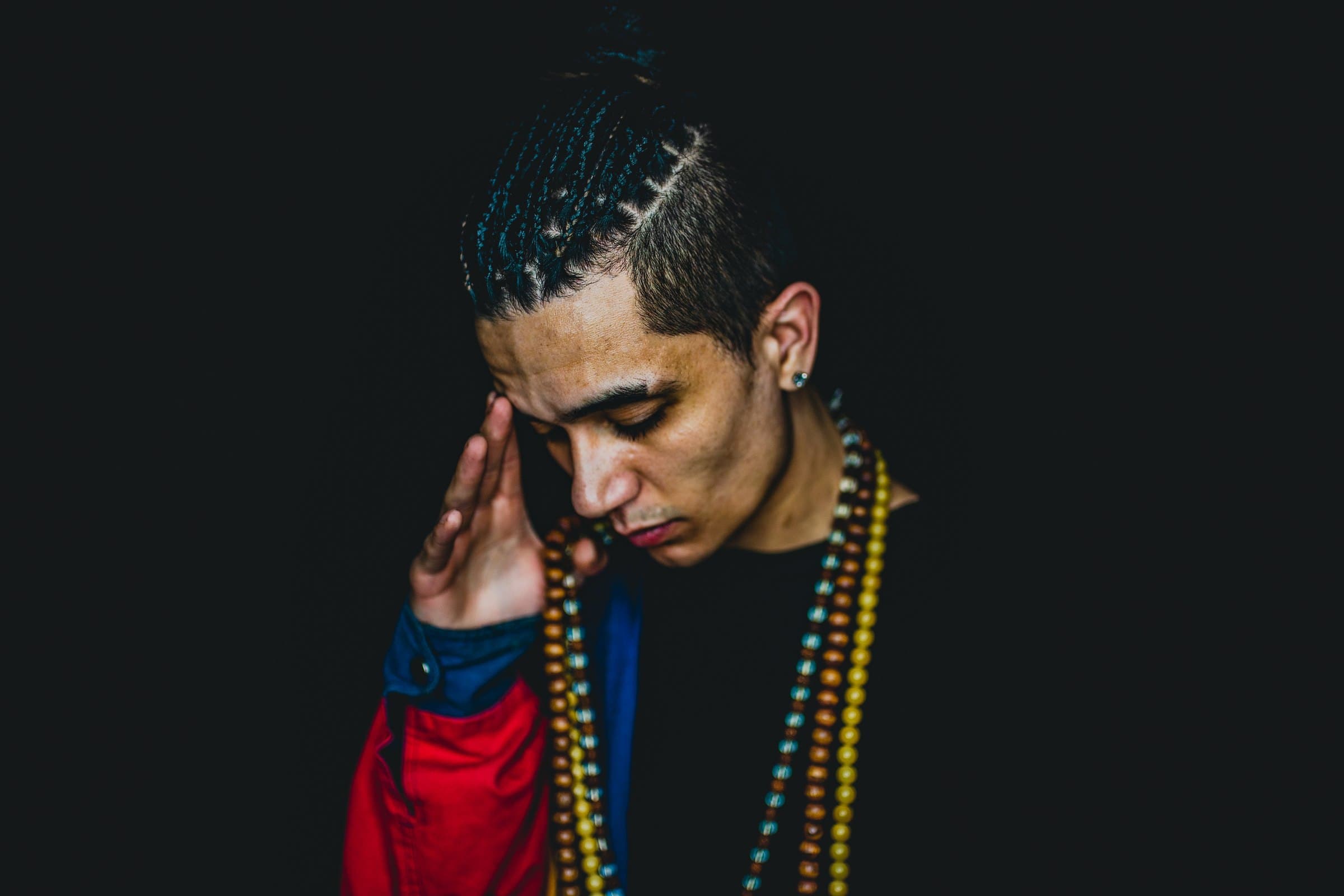 Bdice in a red jacket and beads against a black background